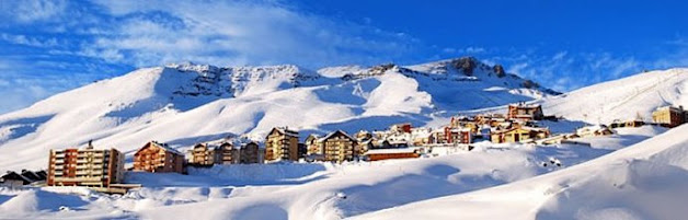 Montanhas nevadas e construções em uma estação de esqui no Chile.
